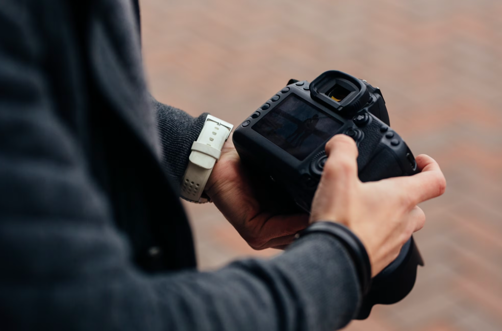 A photographer holding a professional camera and looking at photos outdoors.