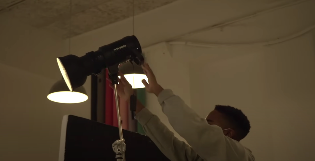 A man in longsleeves setting up studio lighting.